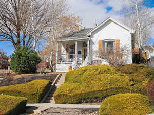 Bungalow featuring covered porch, a chimney, stairway, and stucco siding