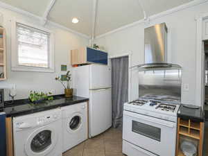 Kitchen featuring independent washer and dryer, white appliances, ventilation hood, and light tile patterned floors