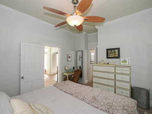 Bedroom with ornamental molding and a ceiling fan