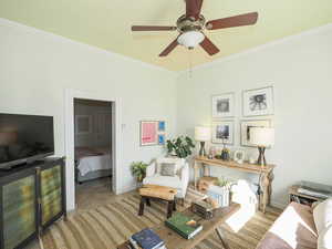 Living room with light tile patterned floors, baseboards, ornamental molding, and ceiling fan