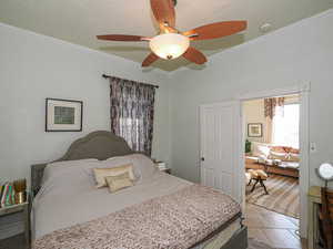 Bedroom featuring crown molding, stone tile floors, and ceiling fan