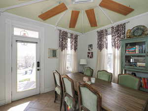 Dining space featuring light tile patterned floors and vaulted ceiling