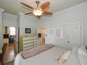 Bedroom with a ceiling fan, a sink, crown molding, dark tile patterned floors, and a closet