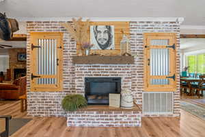 Living room featuring a fireplace, ornamental molding, hardwood / wood-style flooring, and a textured ceiling