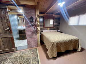 Bedroom with concrete flooring, concrete block wall, a sink, and beamed ceiling