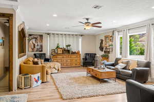 Living room featuring light wood-type flooring, crown molding, and a textured ceiling