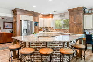 Kitchen with appliances with stainless steel finishes, a kitchen breakfast bar, light stone countertops, light hardwood / wood-style floors, and a kitchen island