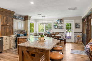 Kitchen featuring hanging light fixtures, a center island, light hardwood / wood-style floors, and light stone counters