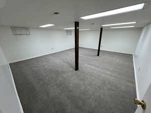 Finished basement with dark colored carpet, visible vents, and baseboards