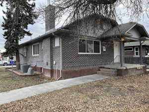 View of front of house with brick siding, fence, and a chimney