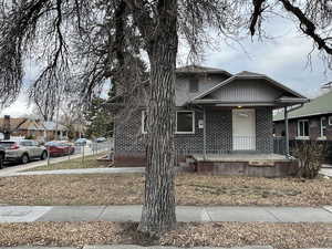 View of front facade with a porch, brick siding, and fence