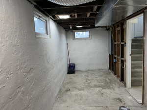 Basement with stairs, a textured wall, and electric panel