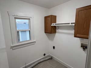 Laundry room with cabinet space, light tile patterned floors, baseboards, hookup for a washing machine, and hookup for an electric dryer