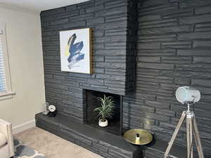 Interior details featuring ornamental molding, carpet flooring, a stone fireplace, and baseboards