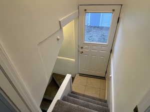 Doorway to outside with stairs and light tile patterned flooring