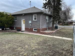 Exterior space with a yard, central AC, brick siding, and fence