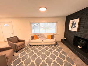 Carpeted living room with ornamental molding, a stone fireplace, and baseboards