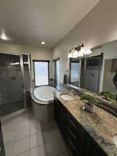 Full bath featuring a garden tub, tile patterned flooring, vanity, and a shower stall