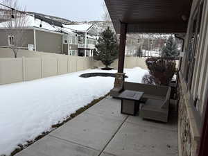 Snow covered patio featuring a fenced backyard