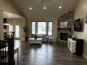 Living area with a fireplace, recessed lighting, dark wood-type flooring, high vaulted ceiling, and baseboards