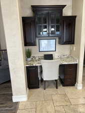 Interior space featuring stone tile flooring, built in study area, and baseboards