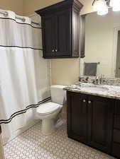 Bathroom featuring toilet, shower / bath combination with curtain, vanity, and an inviting chandelier