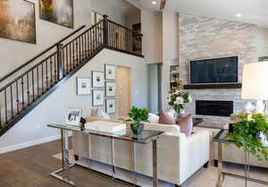 Living room featuring baseboards, a glass covered fireplace, stairway, dark wood-type flooring, and high vaulted ceiling