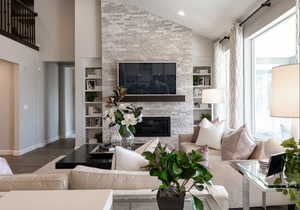 Living room with baseboards, wood finished floors, a wealth of natural light, and a glass covered fireplace