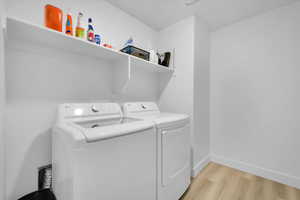 Laundry room with baseboards, laundry area, independent washer and dryer, and light wood-style floors