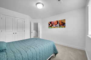 Bedroom with baseboards, a closet, visible vents, and light colored carpet