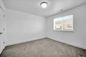 Spare room featuring carpet, visible vents, and baseboards