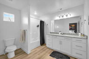 Bathroom featuring toilet, wood finished floors, visible vents, vanity, and baseboards