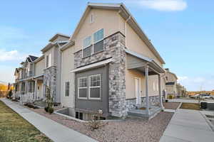 View of side of home featuring stone siding, a residential view, and stucco siding