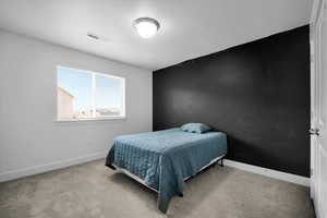 Bedroom with baseboards, visible vents, and light colored carpet