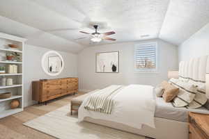 Bedroom with visible vents, light colored carpet, vaulted ceiling, and a textured ceiling