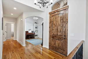 Foyer entrance featuring light wood finished floors, baseboards, arched walkways, and recessed lighting