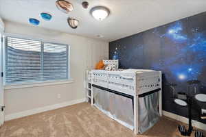 Bedroom featuring a textured ceiling, light carpet, visible vents, and baseboards