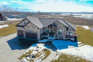 View of front of house with an attached garage, a mountain view, concrete driveway, stone siding, and stucco siding