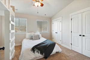 Bedroom with light colored carpet, visible vents, baseboards, vaulted ceiling, and two closets