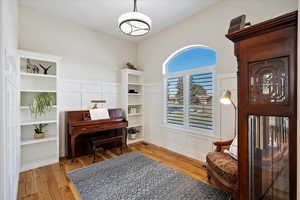 Living area featuring a decorative wall, wood finished floors, and wainscoting