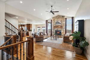 Living area with light wood-style flooring, recessed lighting, a fireplace, vaulted ceiling, and stairway