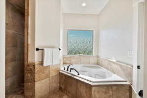 Full bathroom with a jetted tub and tile walls