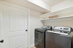 Washroom featuring laundry area, baseboards, and washer and clothes dryer