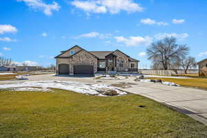 French country style house with a garage, concrete driveway, stone siding, fence, and a front lawn