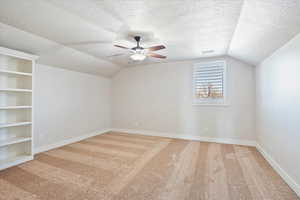 Additional living space featuring carpet floors, visible vents, vaulted ceiling, and a textured ceiling