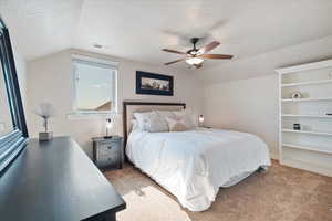 Bedroom with vaulted ceiling, a textured ceiling, light carpet, and visible vents