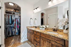 Bathroom with a sink, a spacious closet, baseboards, and double vanity