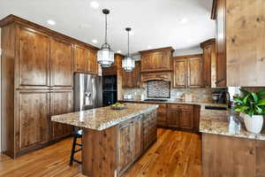 Kitchen with stainless steel appliances, a sink, light wood-type flooring, a center island, and pendant lighting