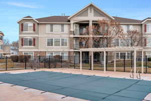 Community pool with a patio area, hot tub, fence, and a pergola