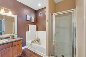 Full bathroom with a garden tub, separate shower, wood finished floors, and vanity